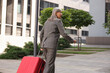 © New Africa - Being late. Senior businesswoman with red suitcase running outdoors