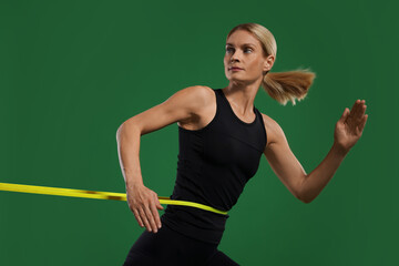 Poster - Athletic woman exercising with elastic resistance band on green background