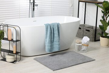 Poster - Stylish bathroom interior with bath tub, houseplants and soft light grey mat