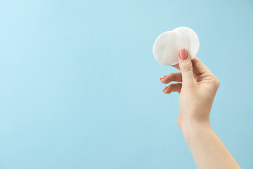 Wall Mural - Woman holding cotton pads on light blue background, closeup. Space for text