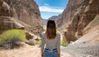 a young woman alone in nature seen from behind in front of a canyon ready to cross the desert a journey through the difficulties and trials of life towards the unknown adventure and freedom
