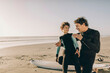 © Marko Geber - Father giving surfing tips to son at the beach