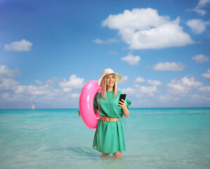 Wall Mural - Young woman with a swimming ring browsing on a smartphone