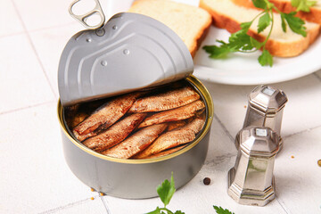 Wall Mural - Canned smoked sprats and plate with bread on white tile background