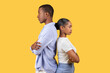 Black couple standing back-to-back, arms crossed, on yellow background