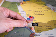 This evocative image captures a hand placing pins adorned with the flags of the USA, UK, and a pirate insignia onto a map of the Red Sea region. It symbolically represents the intricate geopolitical
