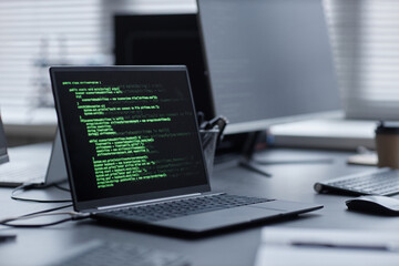 Operating laptop on office desk with running code on screen in cybersecurity department