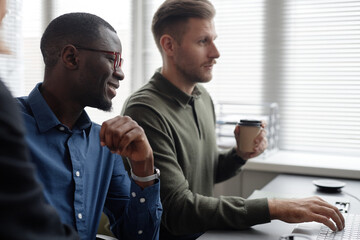 side view with focus on smiling african american male it professional wearing glasses working on cod