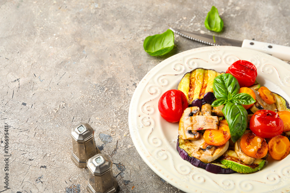 Plate with grilled vegetables and basil on grey background