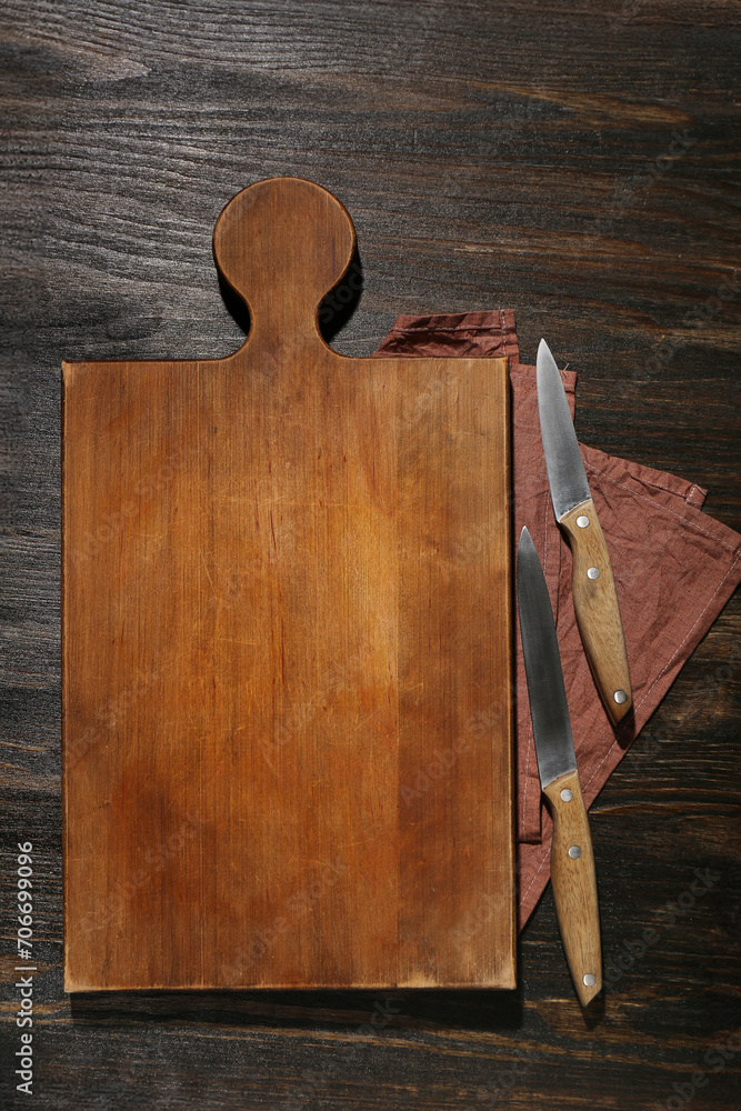 New cutting board and knives on wooden background