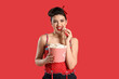Young pin-up woman with popcorn on red background