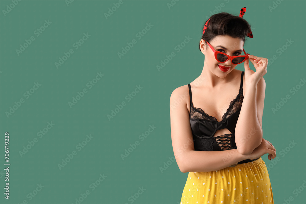 Young pin-up woman in sunglasses on green background