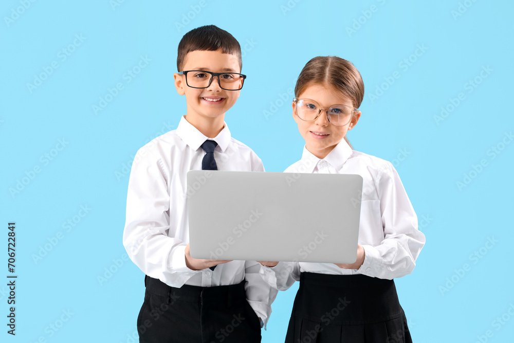Little business colleagues using laptop on blue background. Opposite Day celebration