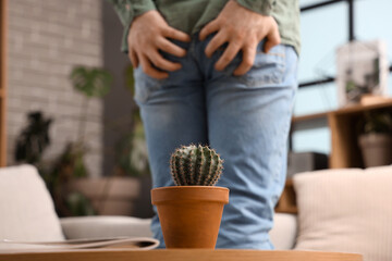 Wall Mural - Cactus on table of young man with hemorrhoids at home, closeup