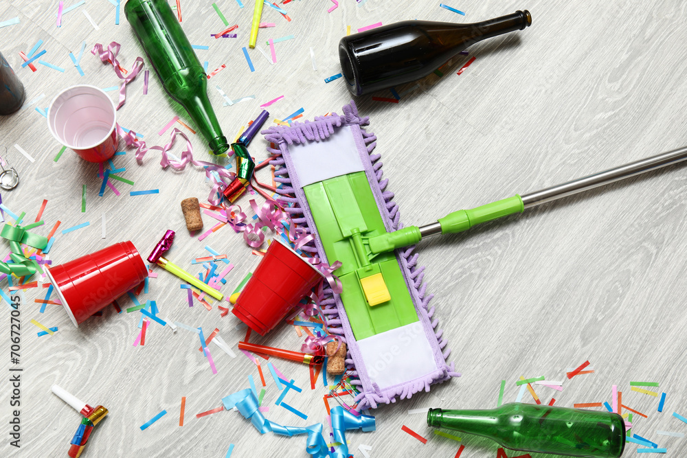 Mop with mess on light wooden floor after party, top view