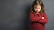 Mad female kid, angry little girl standing with her arms crossed, and looking at the camera with upset face expression. Unhappy toddler, studio shot, annoyed and frustrated child emotion