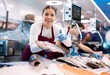 © JackF - Positive young saleswoman demonstrating seabass to client in fish store with large stock