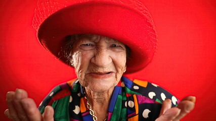 Poster - Unhappy displeased fisheye portrait caricature of funny elderly woman saying NO with red hat isolated on red background.