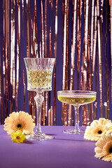 Wall Mural - Front view of two glasses filled with wine displayed on purple table. Few flowers featured. New Year Party background greeting concept. Template design