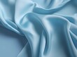 light grayish azure color satin fabric silk for background. blue fabric textile drape with crease wavy folds, wind movement, background, texture.