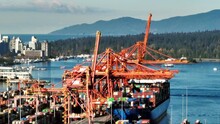 Port Crane Unloading Containers From Ship Docked At The Terminal. GCT Vanterm In Vancouver, BC, Canada. Aerial Sideways Shot