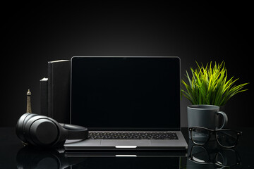 Sticker - Laptop with black screen on working desk with cup and earphones on black background