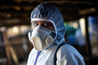 A focused healthcare professional wearing a protective suit and respirator mask.