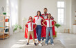 Portrait of fun happy family with two children playing together and pretending to be superheroes. Mom, dad, son and daughter in red Superhero capes hold their hands to sides at home in living room.