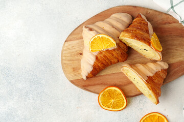 Wall Mural - Glazed croissant with dried orange on wooden board