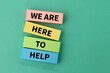 © Fauzi - colored paper with the words WE ARE HERE TO HELP. service concept