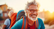 Portrait happy elder man hiker with backpacks walks in mountains at sunset, elderly tourist adventure.