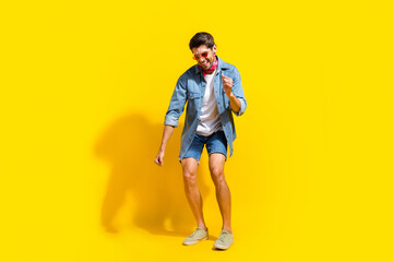 Poster - Full body photo of optimistic cool man dressed denim shirt shorts in glasses dancing on black friday isolated on yellow color background