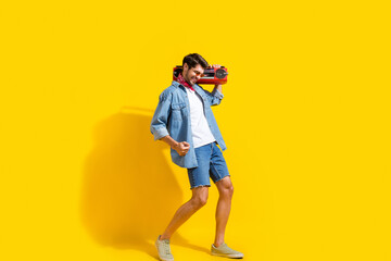 Sticker - Full body photo of good mood man dressed denim shirt shorts in glasses dance with boombox on shoulder isolated on yellow color background