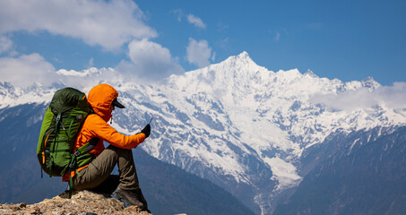 Wall Mural - Woman backpacker taking photo of  high altitude mountains with smart phone