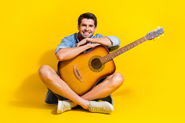 Sticker - Full size photo of cheerful pleasant guy with bristle wear jeans jacket sitting with acoustic guitar isolated on yellow color background