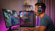 © Prathankarnpap - Side view of joyful male gamer in headphone playing video game on computer at home