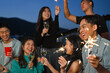 © Prathankarnpap - Group of young adult friends having fun a party on the rooftop with sparklers during sunset