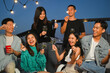 © Prathankarnpap - Group of young adult friends laughing and having fun at rooftop party. Friendship lifestyle concept