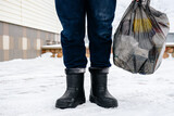 Fototapeta  - Man taking out the trash outside in winter.