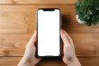 © TaniaC. - Vista superior de mano de mujer sosteniendo teléfono inteligente con pantalla vacía para introducir imágen y texto sobre fondo de mesa de madera.