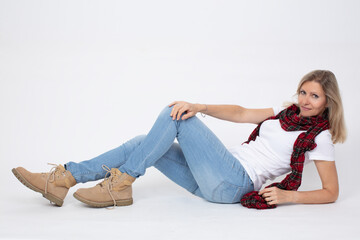 Wall Mural - Adult beautiful slender woman in jeans and boots posing while lying in the studio.