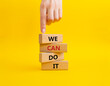 We can do it symbol. Concept words We can do it on wooden blocks. Beautiful yellow background. Businessman hand. Business and We can do it concept. Copy space.