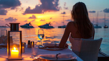 Romantic Dinner On Sunset. Woman Sitting Alone On Table Set With Lantern For A Romantic Meal On Beach, Yachts And Ocean On Background. Dinner For A Couple In Love In Luxury Outdoor Restaurant
