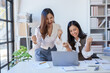 © amnaj - Excited asian business woman celebrating victory together on laptop computer in office.