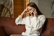 © Grustock - Close-up of a frustrated sad young woman talking on her smartphone while sitting on the couch in the living room at home receives bad news.