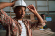 African American adjusts hardhat before working in carpentry factory 