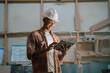 © Prins Productions - African American wears hardhat while smiling when looking at tablet in carpentry warehouse
