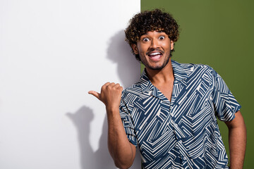 Photo of young crazy hispanic guy in shirt surprised direct finger information banner presentation isolated on khaki color background