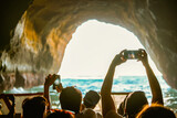 Fototapeta Desenie - Tourist sightseeing and taking photos with smartphones inside the cave on Algarve coast, Albufeira, Portugal