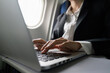 © itchaznong - businesswoman flying and working in an airplane in first class, sitting inside an airplane using laptop